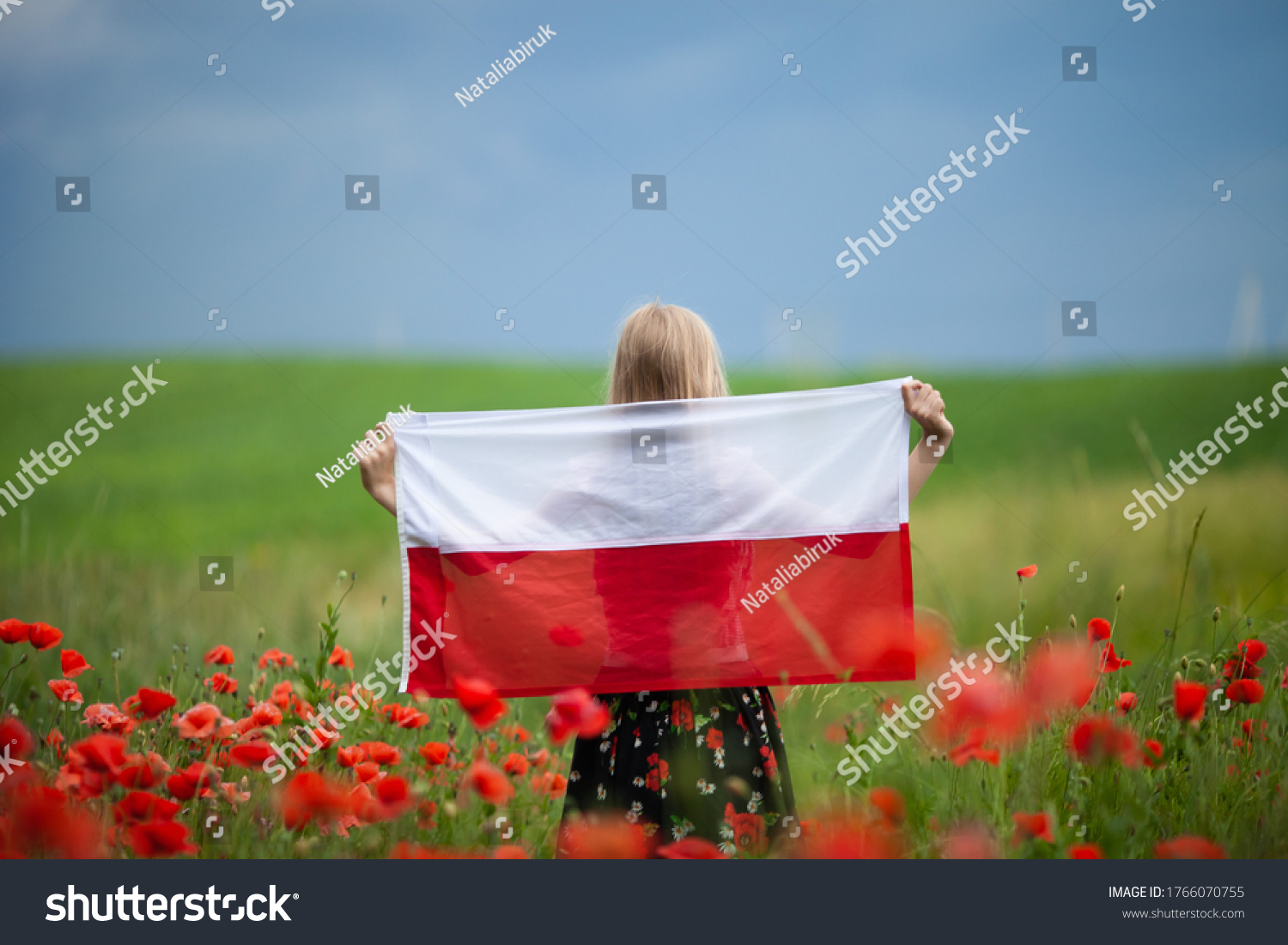 Blond girl holding flag of Poland in the poppy field. Back  view. Polish Flag Day. Independence Day. Travel and learn polish language concept. #1766070755