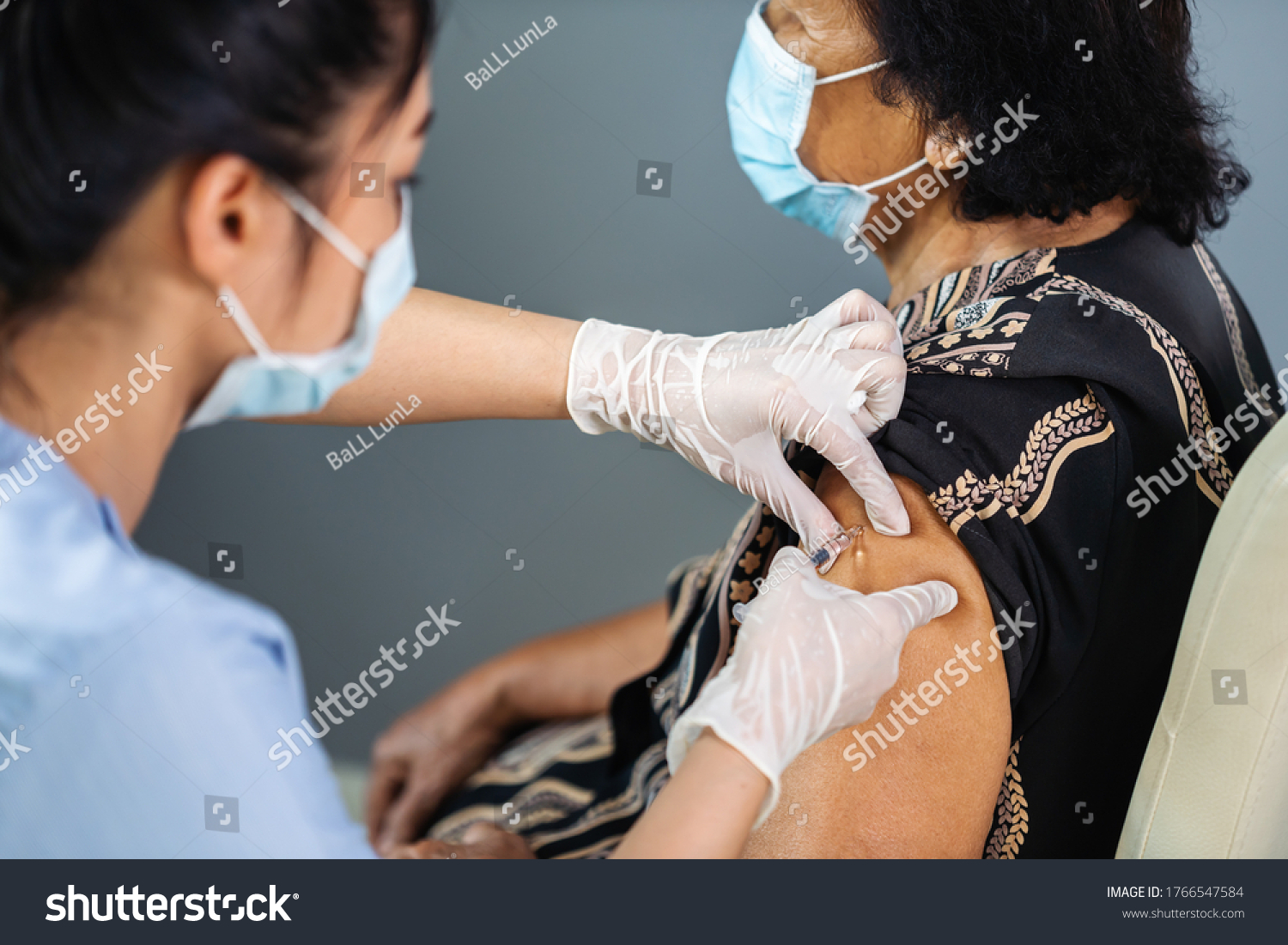 doctor in gloves holding syringe and making injection to senior patient in medical mask. Covid-19 or coronavirus vaccine #1766547584
