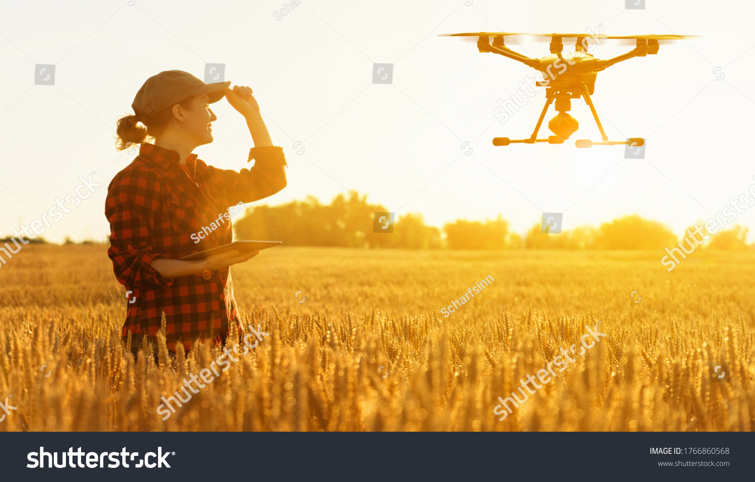 Woman farmer controls drone with a tablet. Smart farming and precision agriculture #1766860568