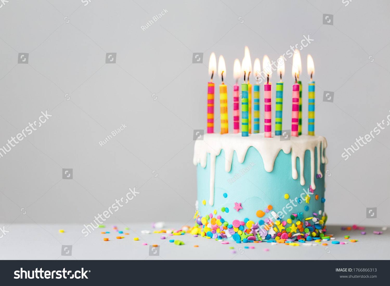 Birthday cake with white drip icing, sprinkles and colorful birthday candles #1766866313