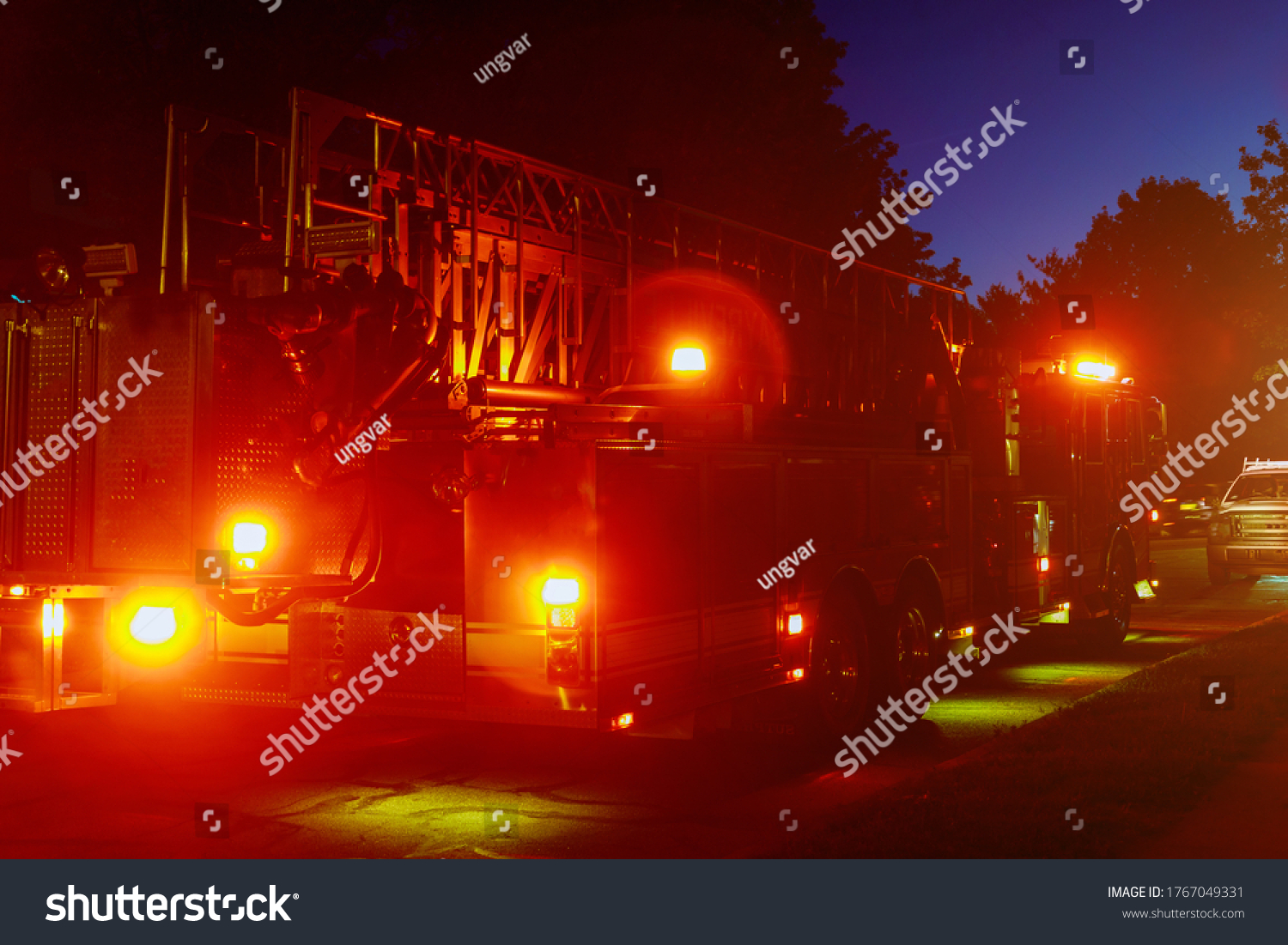 Fire truck with flashing red lights of a fire engine night time in dusk #1767049331