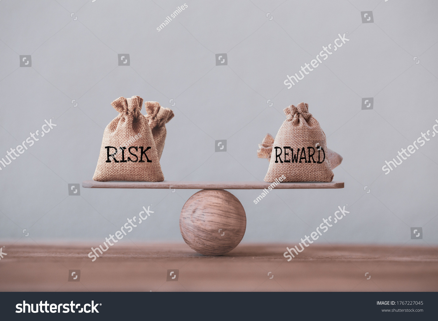 Risk and reward bags on a basic balance scale in equal position on wood table. risk management concept, depicts investors use a risk reward ratio to compare the expected return of an investment #1767227045