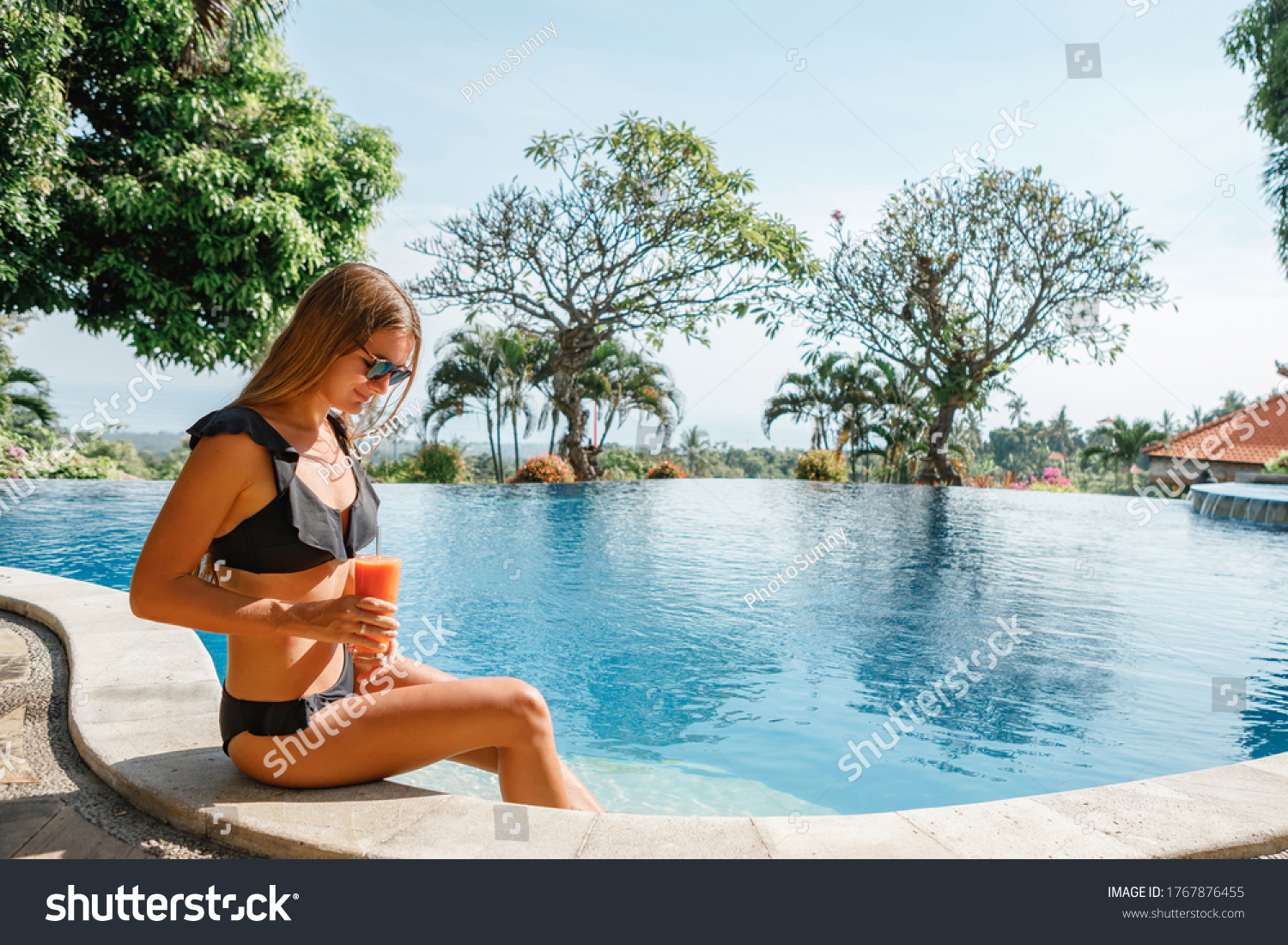 Woman swims to the edge of swimming pool, takes fresh juice, drinks it and swims away, sunny day in the swimming pool outdoors, relaxing in the pool #1767876455