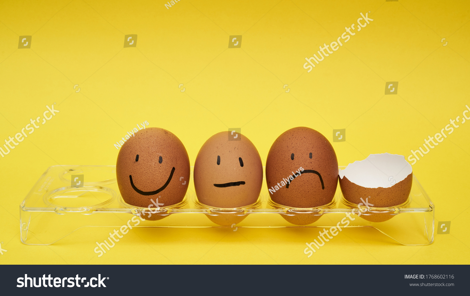 Chicken eggs in an egg holder. Full tray of eggs. Half an egg, egg yolk, shell. Emotion and facial expression painted on eggs #1768602116