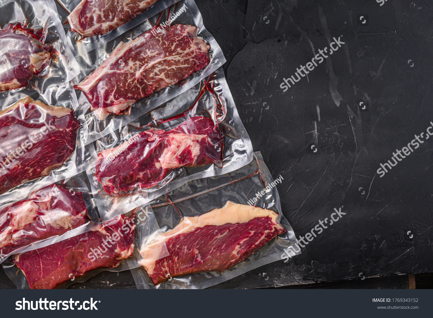 Vacuum packed organic raw beef alternative cuts: top blade, rump, picanha, chuck roll steaks, over black textured background, top view space for text. #1769343152