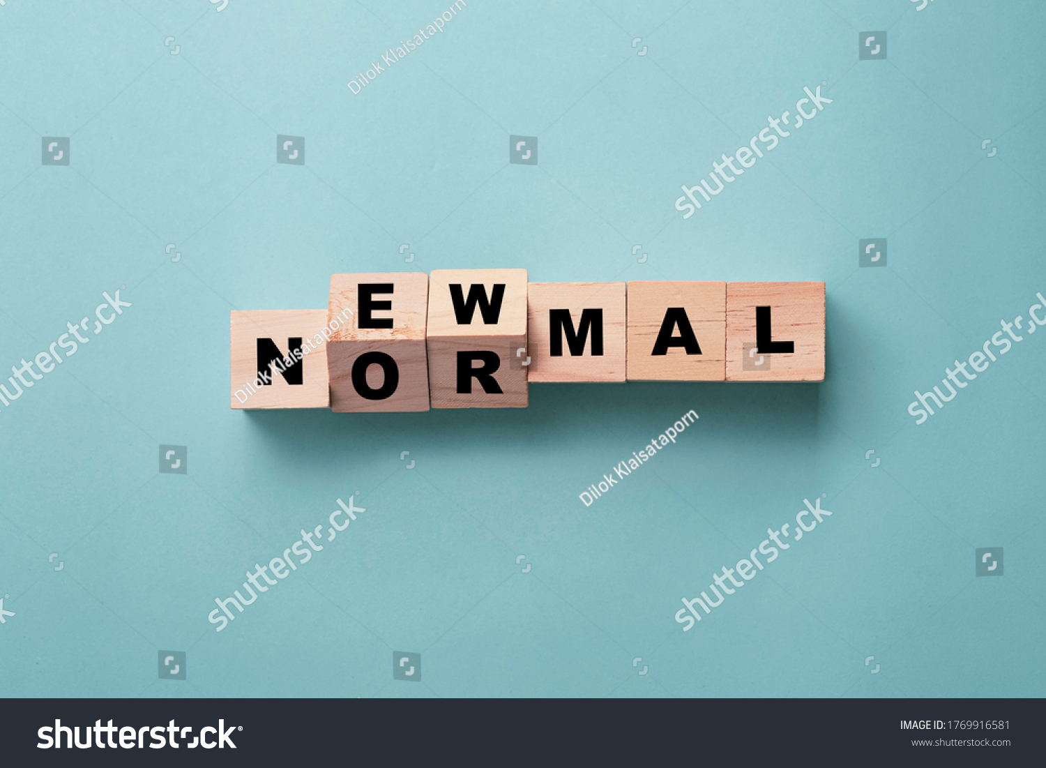 Flipping wooden block cubes for new normal wording on green background. The world is changing to balance it into new normal include business , economy , environment and health. #1769916581