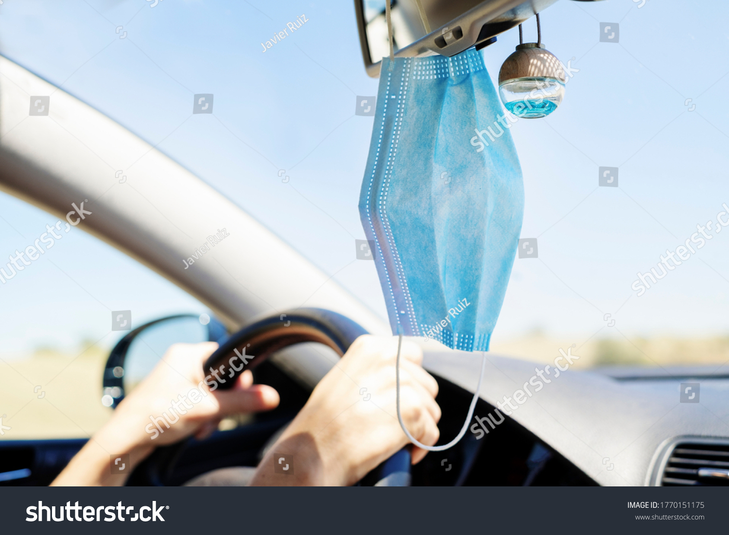 surgical mask hanging from the rear view mirror of a car selective focus #1770151175