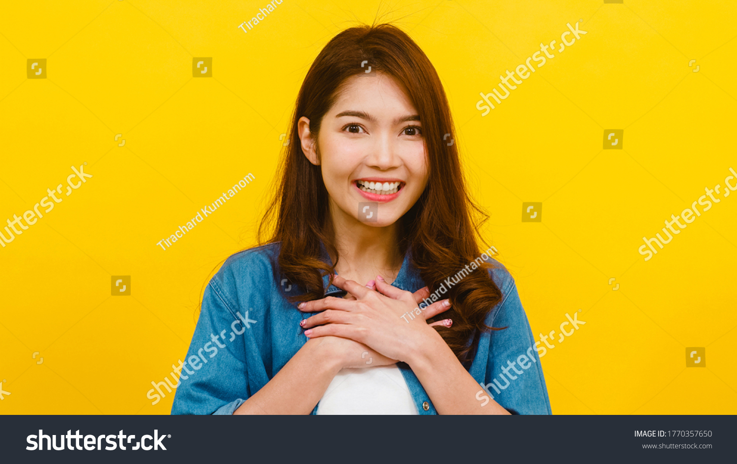 Portrait of young Asian lady with positive expression, joyful and exciting, dressed in casual clothing and looking at the camera over yellow background. Happy adorable glad woman rejoices success. #1770357650