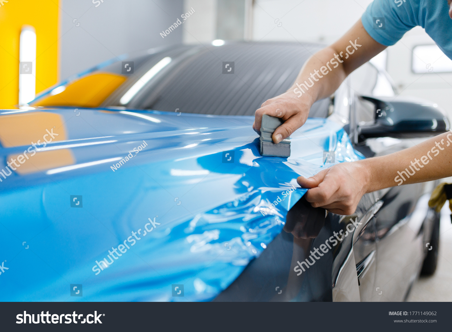 Car wrapping, mechanic with squeegee installs film #1771149062