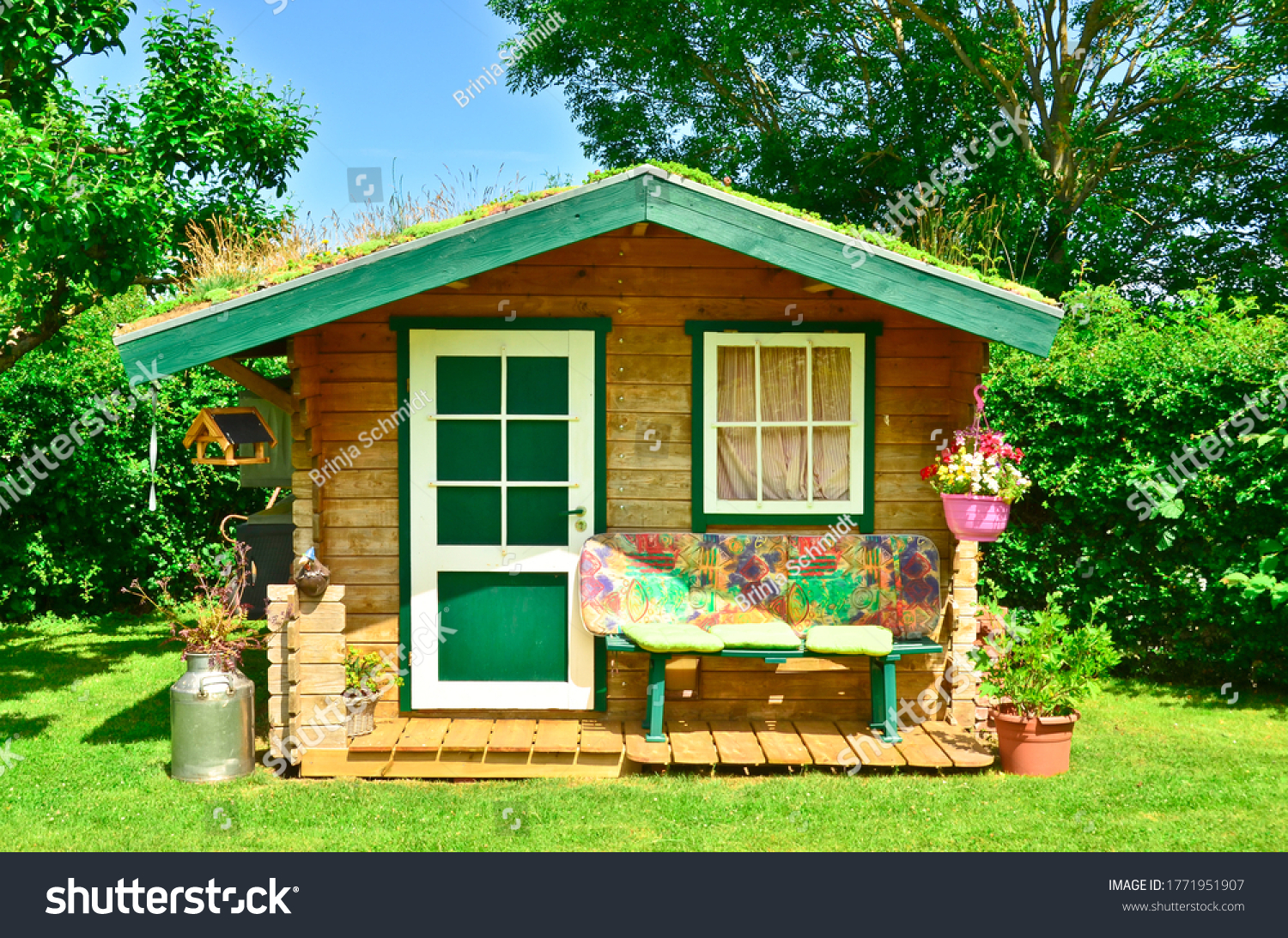 A light green and wooden small shed, gardenhouse, with a bench some tools around it #1771951907