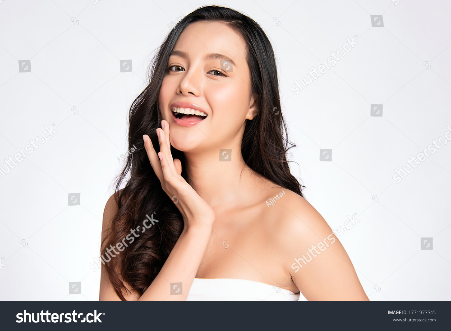Beauty face. Smiling asian woman touching healthy skin portrait. Beautiful happy girl model with fresh glowing hydrated facial skin and natural makeup on white background, #1771977545