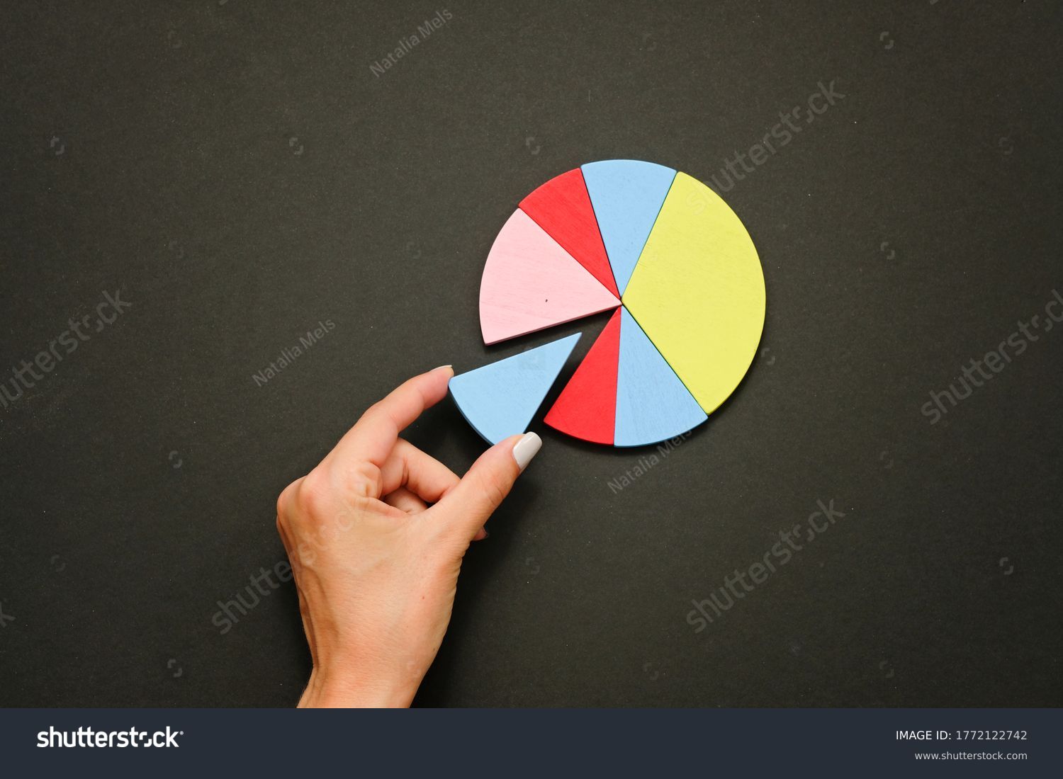 Colorful fraction circles arranged into a circle graph and hand, black background. #1772122742