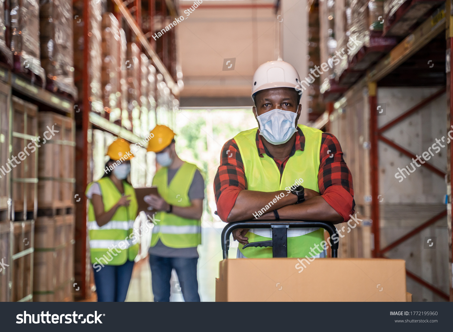 Group of diversity Workers wearing protective face mask working in factory warehouse. Black man pushing metal lathe cart with box parcel during covid 19 pandemic crisis. Logistic industry concept. #1772195960