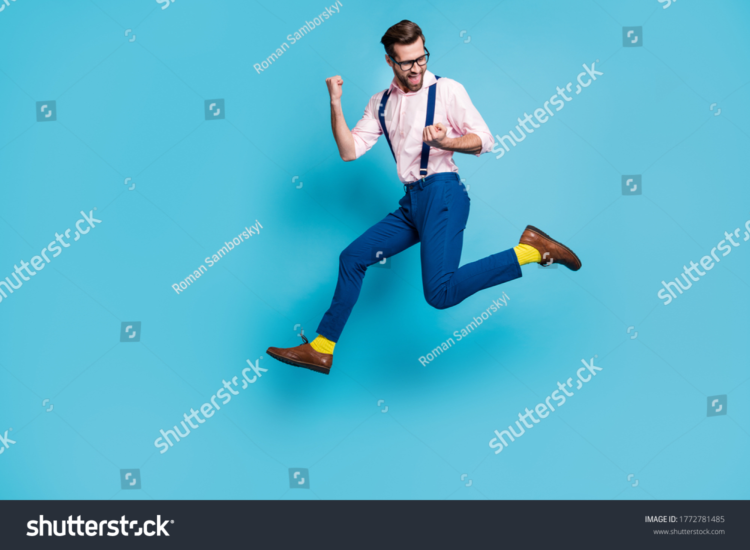 Full size profile photo of handsome man jump high up running competition raise fists first place winner race marathon wear specs shirt suspenders pants boots isolated blue color background #1772781485