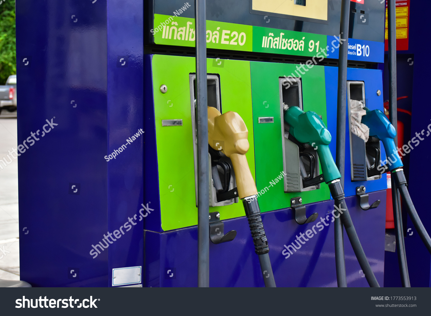 Fuel nozzles at the gas station, Thai language above green nozzle is gasohol 91, above chartreuse green nozzle is gasohol E20, and above blue nozzle is diesel B10 in English. #1773553913