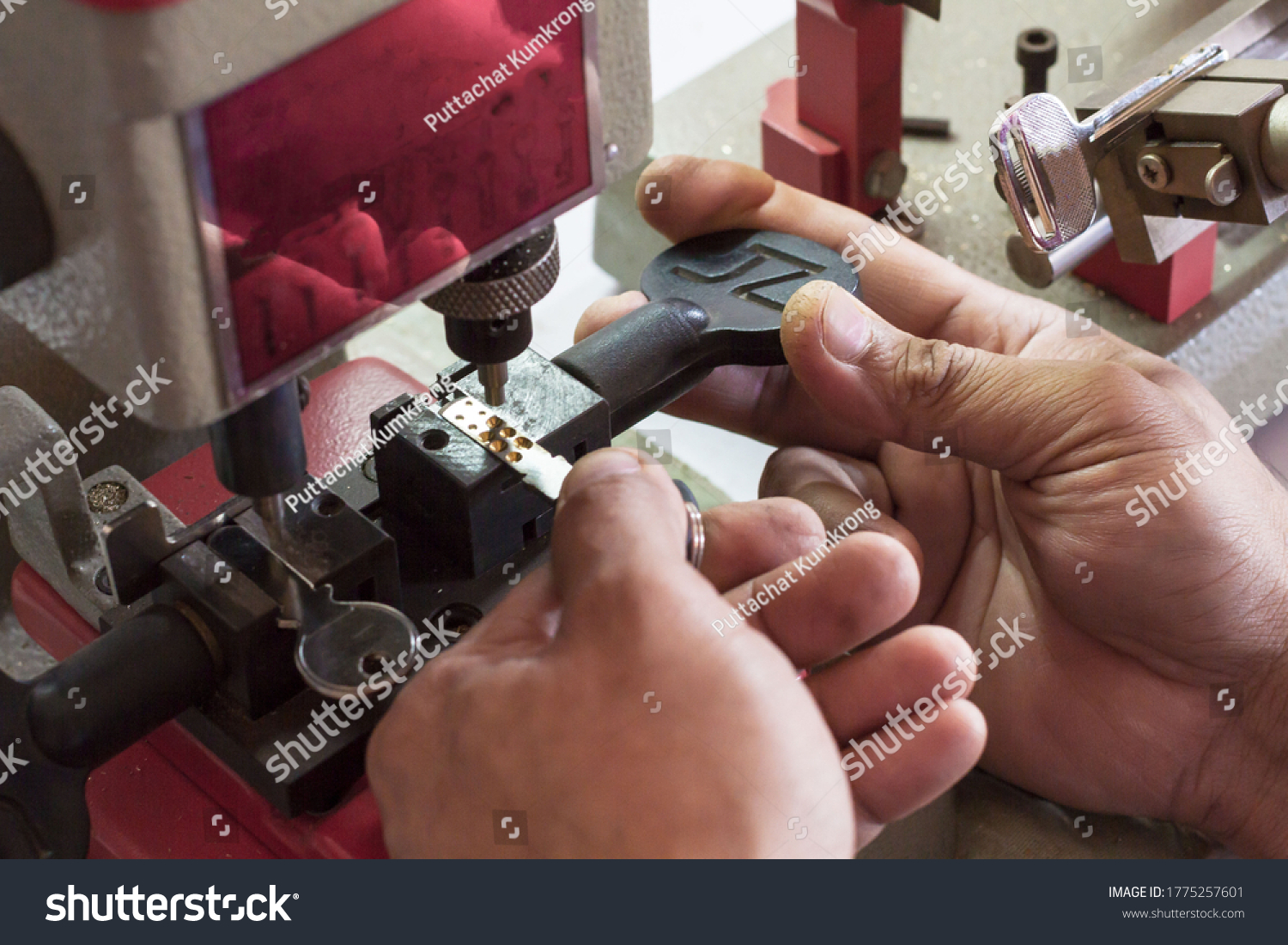 Locksmith in workshop makes new key. Professional making key in locksmith. Machine production of duplicate metal key. #1775257601