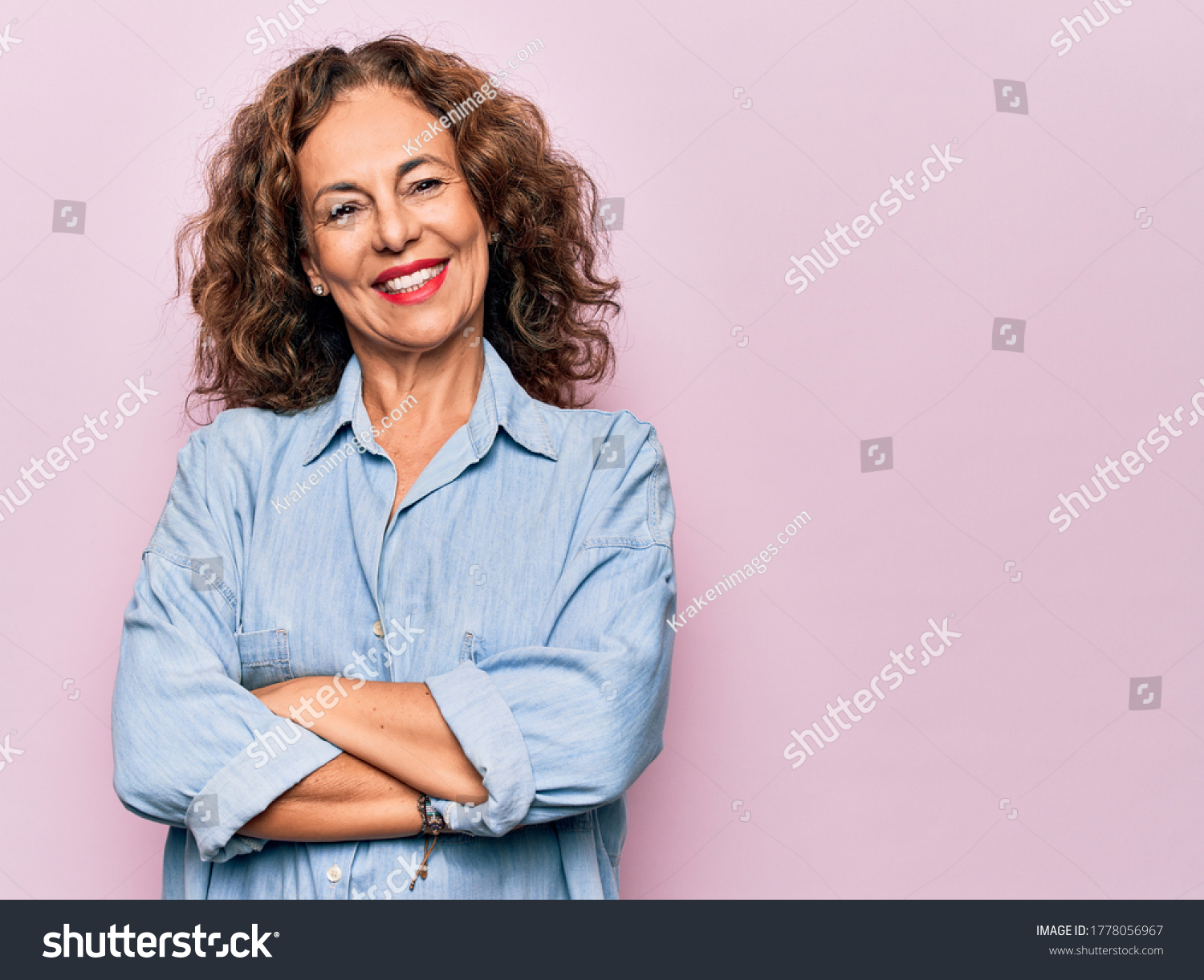 Middle age beautiful woman wearing casual denim shirt standing over pink background happy face smiling with crossed arms looking at the camera. Positive person. #1778056967
