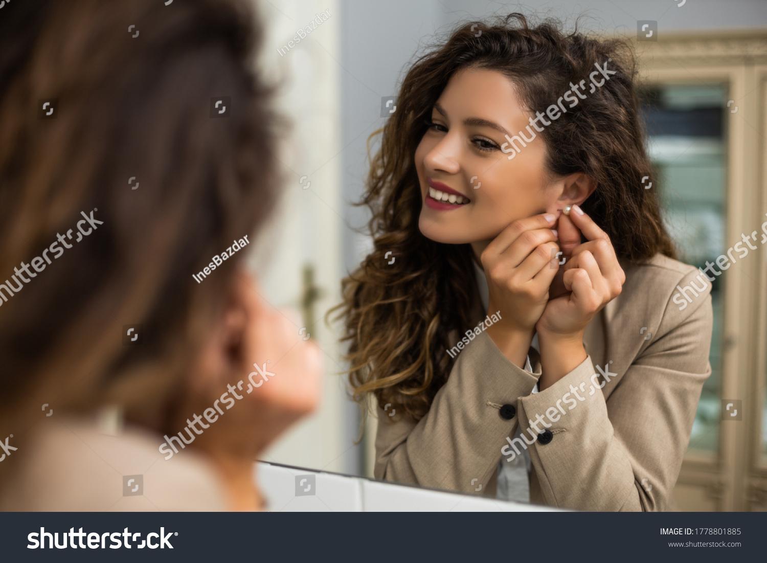 Businesswoman is  putting earrings while preparing for work. #1778801885