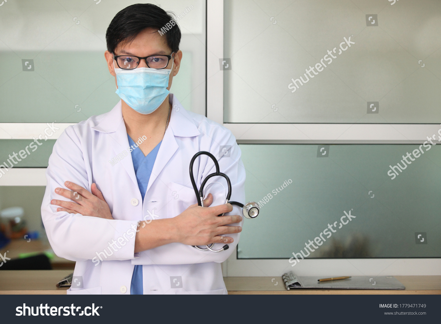 Coronavirus mask doctor wearing face protective mask against corona virus banner panoramic medical professional preventive gear.
and he hold stethoscope with hospital background #1779471749