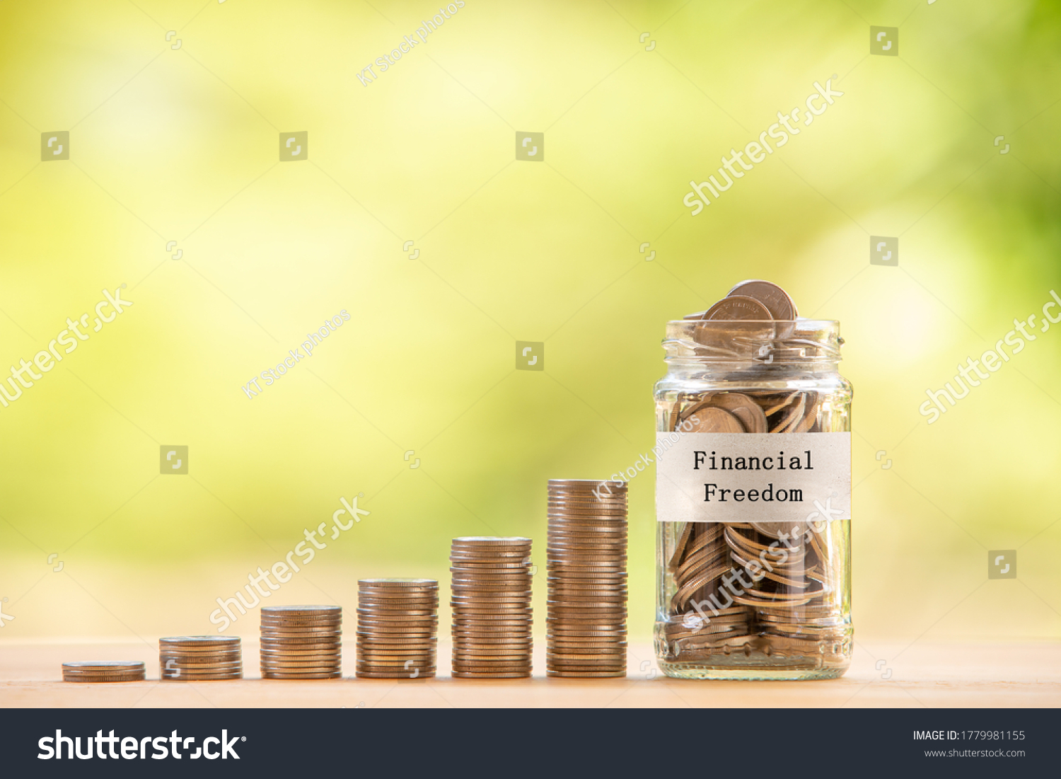 A glass jar with text label "financial freedom" filled with coins placed beside a pile of coins. Saving money for financial independence or financial freedom concept. #1779981155