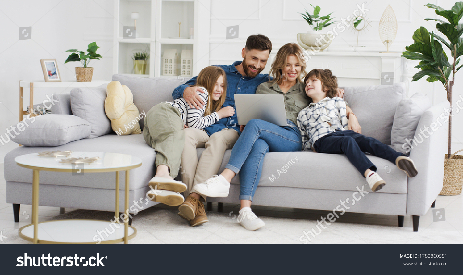 Caucasian parents with kids on couch using gadget. Young man and woman with son and daughter spending time together with laptop. Father and mother watching something online on computer. Rest at home. #1780860551