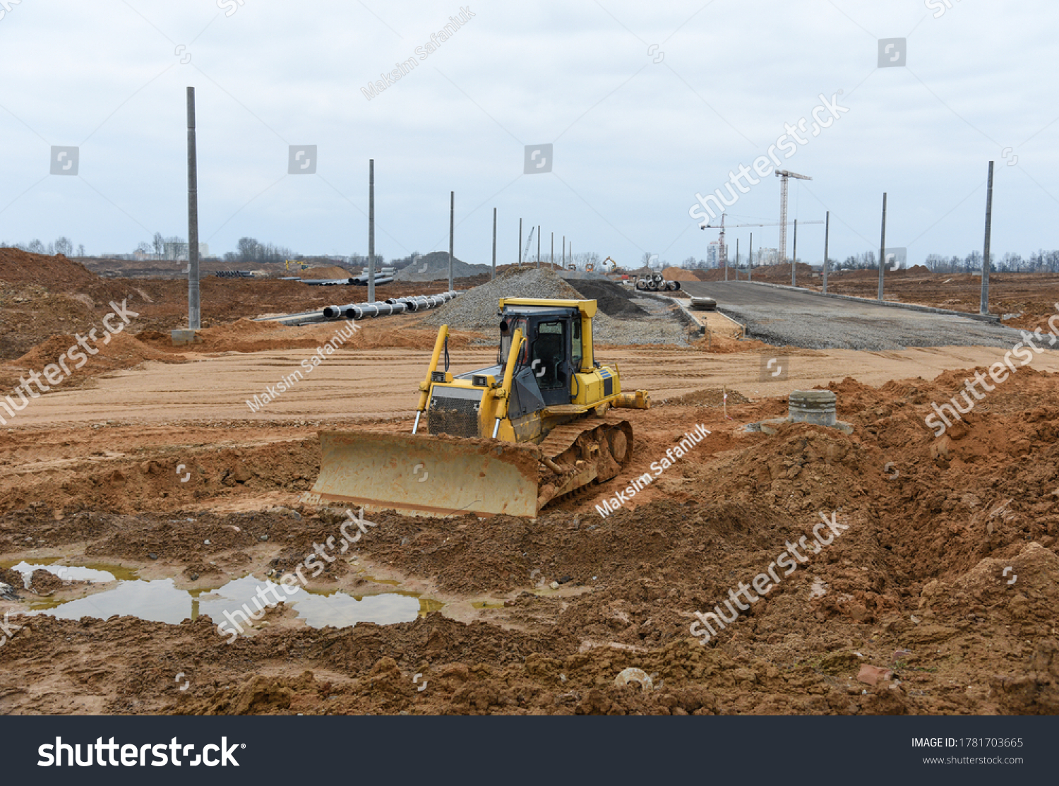 Bulldozer moves gravel during on road work at construction site. Dozer leveling stones for laying asphalt on a new freeway. Heavy machinery for earth-moving #1781703665