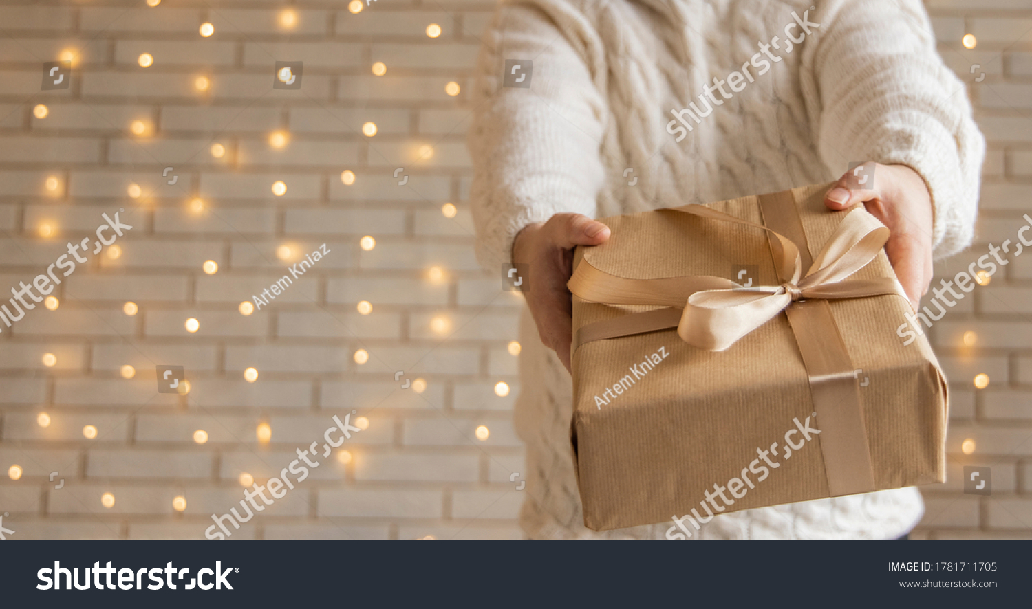 Christmas gift in man hands holiday wallpaper poster concept picture with white wall background and garland illumination lamps  #1781711705