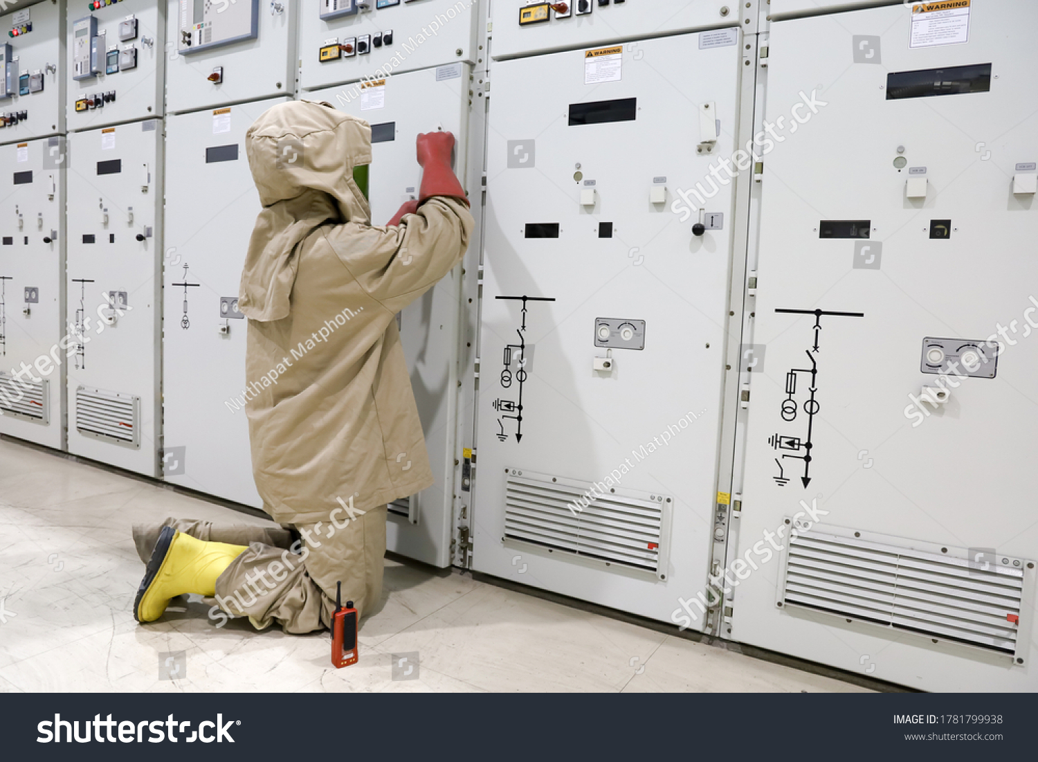 The electrician wear arc flash suit, electrical safety gloves and high voltage insulating boots to open power compartment door for rackout circuit breaker of medium voltage switchgear #1781799938