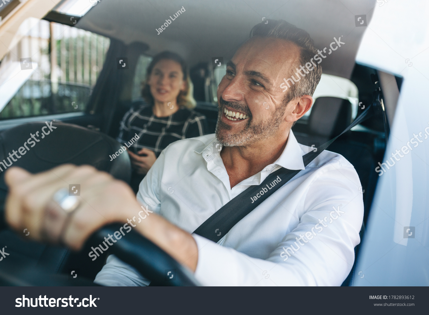 Taxi driver talking to a female passenger sitting in backseat. Businesswoman using taxi ride to go to work. #1782893612