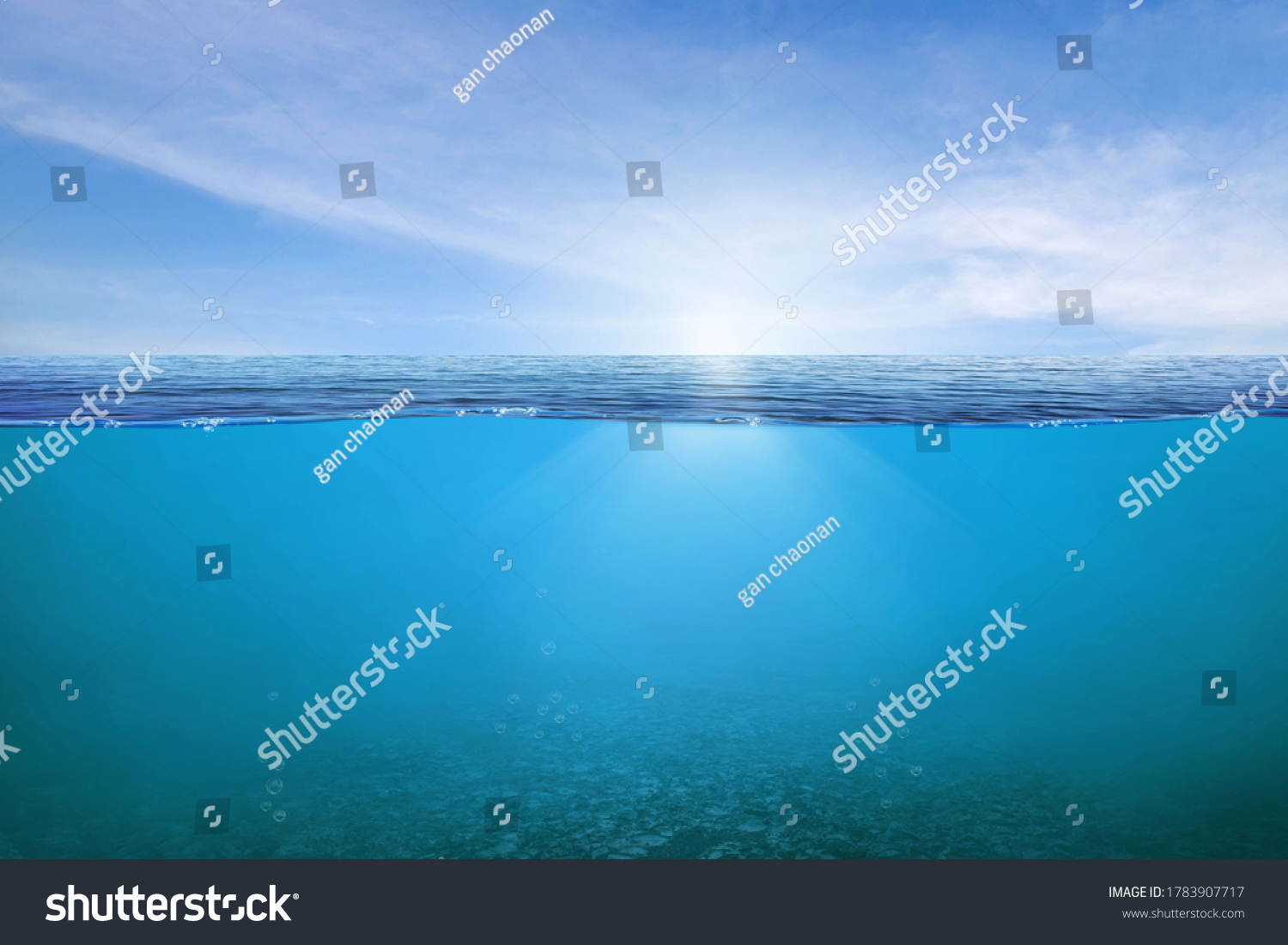 BLUE UNDER WATER waves and bubbles. Beautiful white clouds on blue sky over calm sea with sunlight reflection, Tranquil sea harmony of calm water surface. Sunny sky and calm blue ocean.  #1783907717