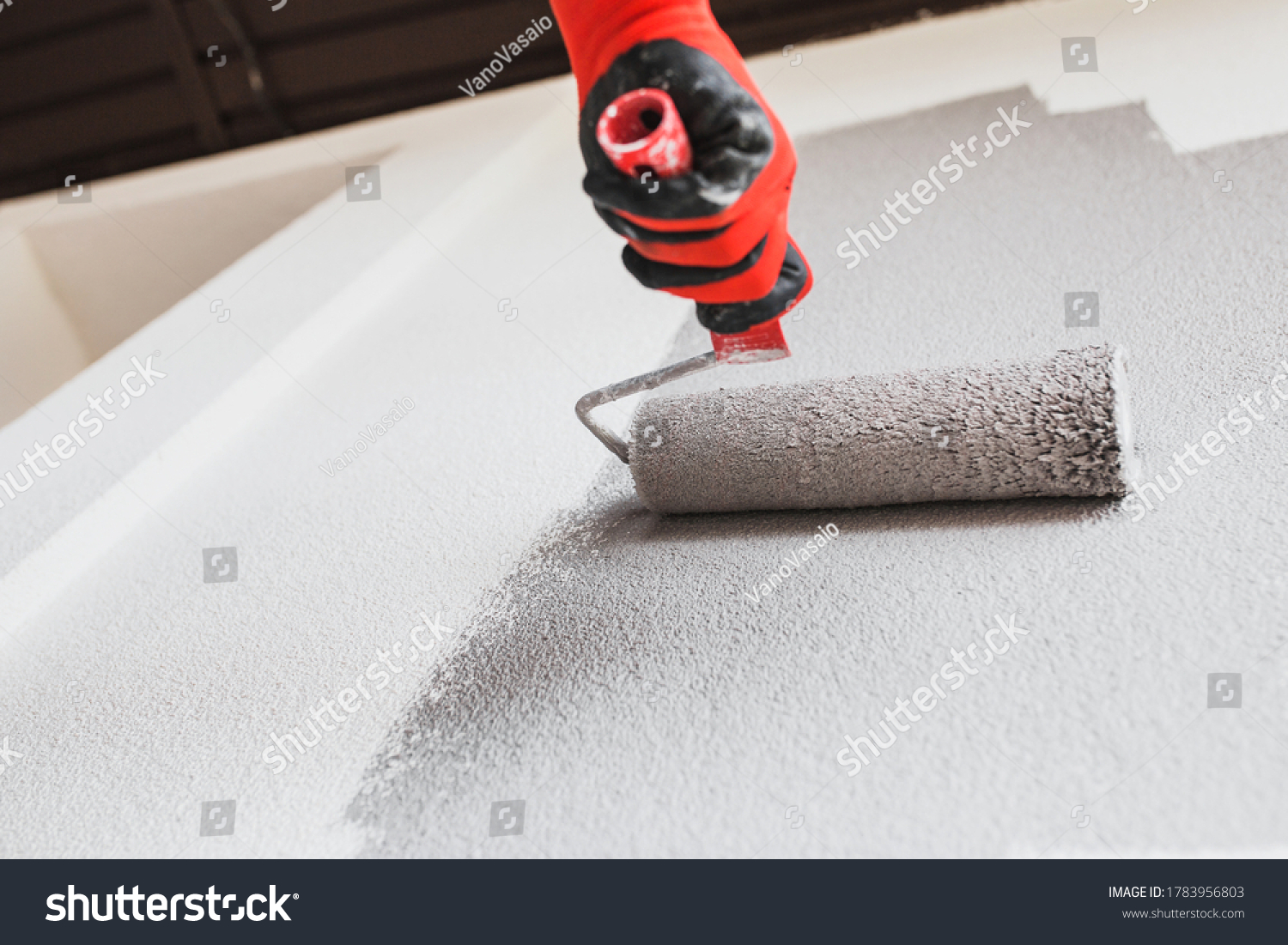 Paint roller on the wall during painting - renovation of the building facade in dark gray #1783956803