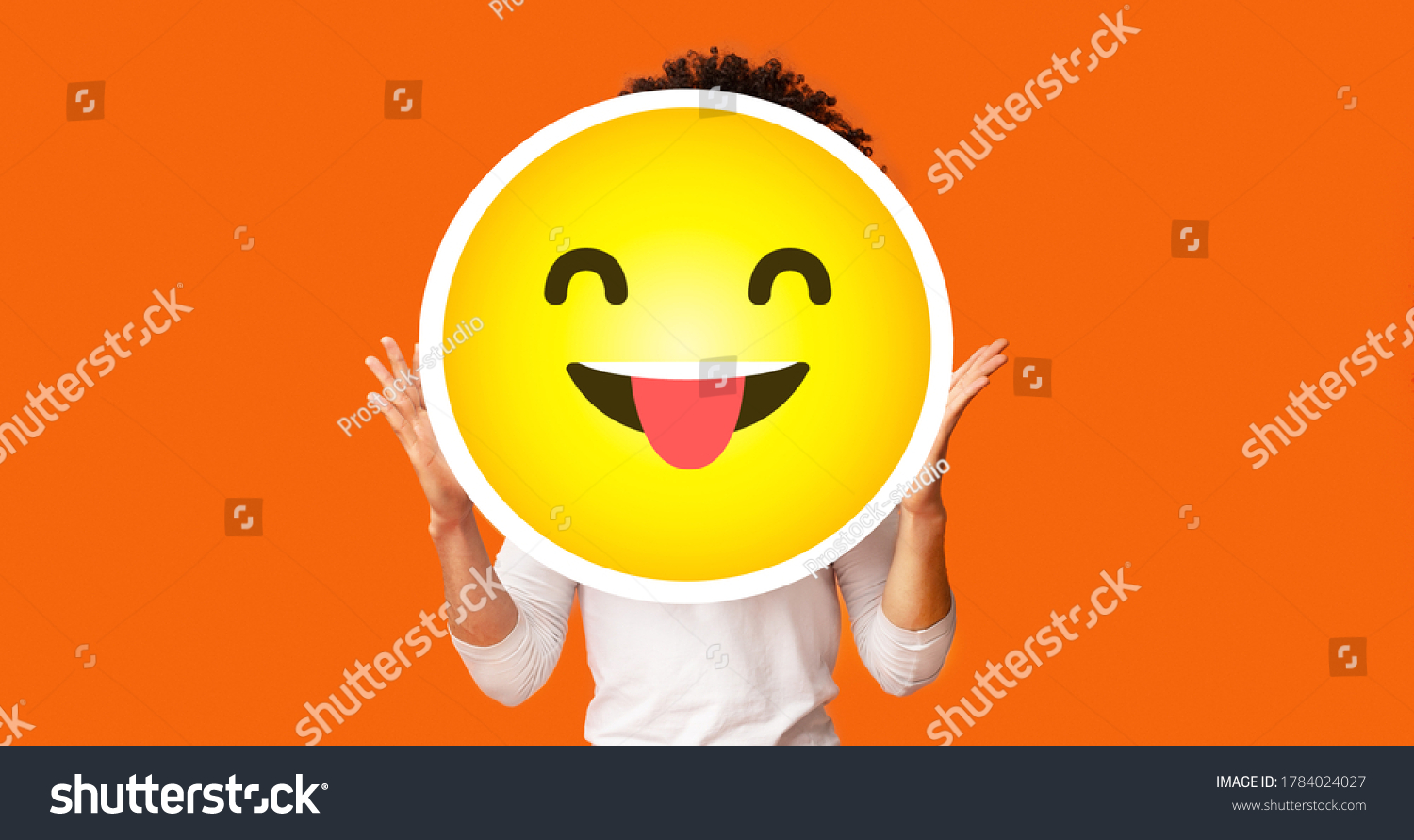 Black bushy man holding happy cheeky emoji emoticon smiley in front of his head, standing over orange studio background, creative collage, empty space #1784024027