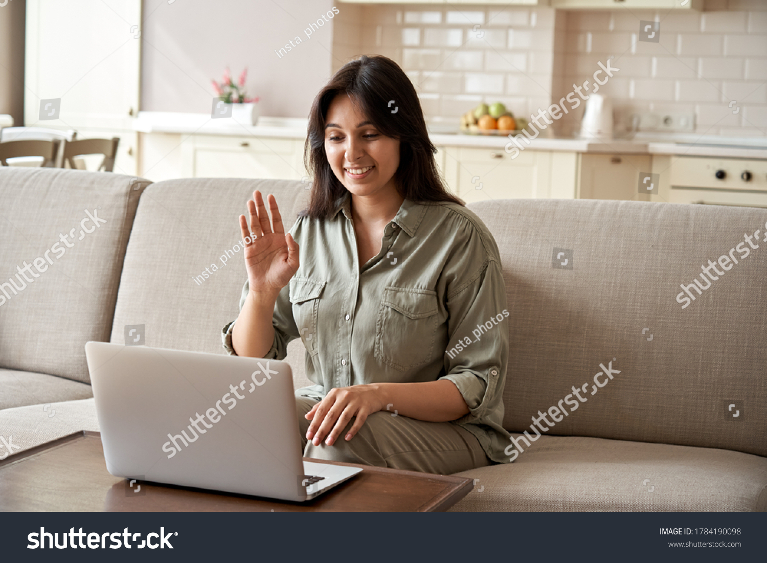 Smiling young indian woman video calling using laptop webcam conference work at home office. Happy lady sit on sofa talk by virtual videoconference meeting dating online using computer app videocall. #1784190098