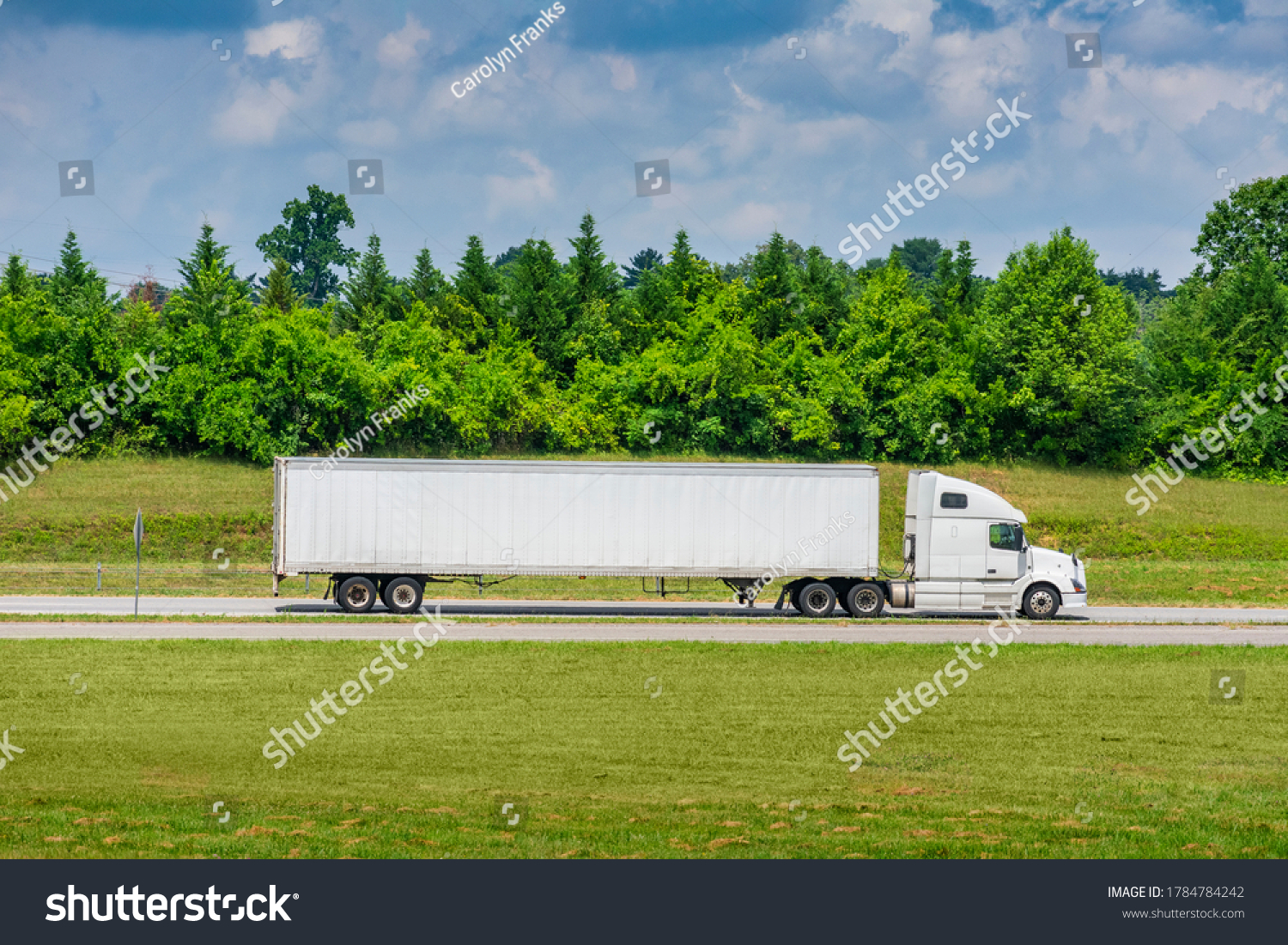 Horizontal side view shot of a white tractor-trailer with a blank trailer that would make great copy space. #1784784242