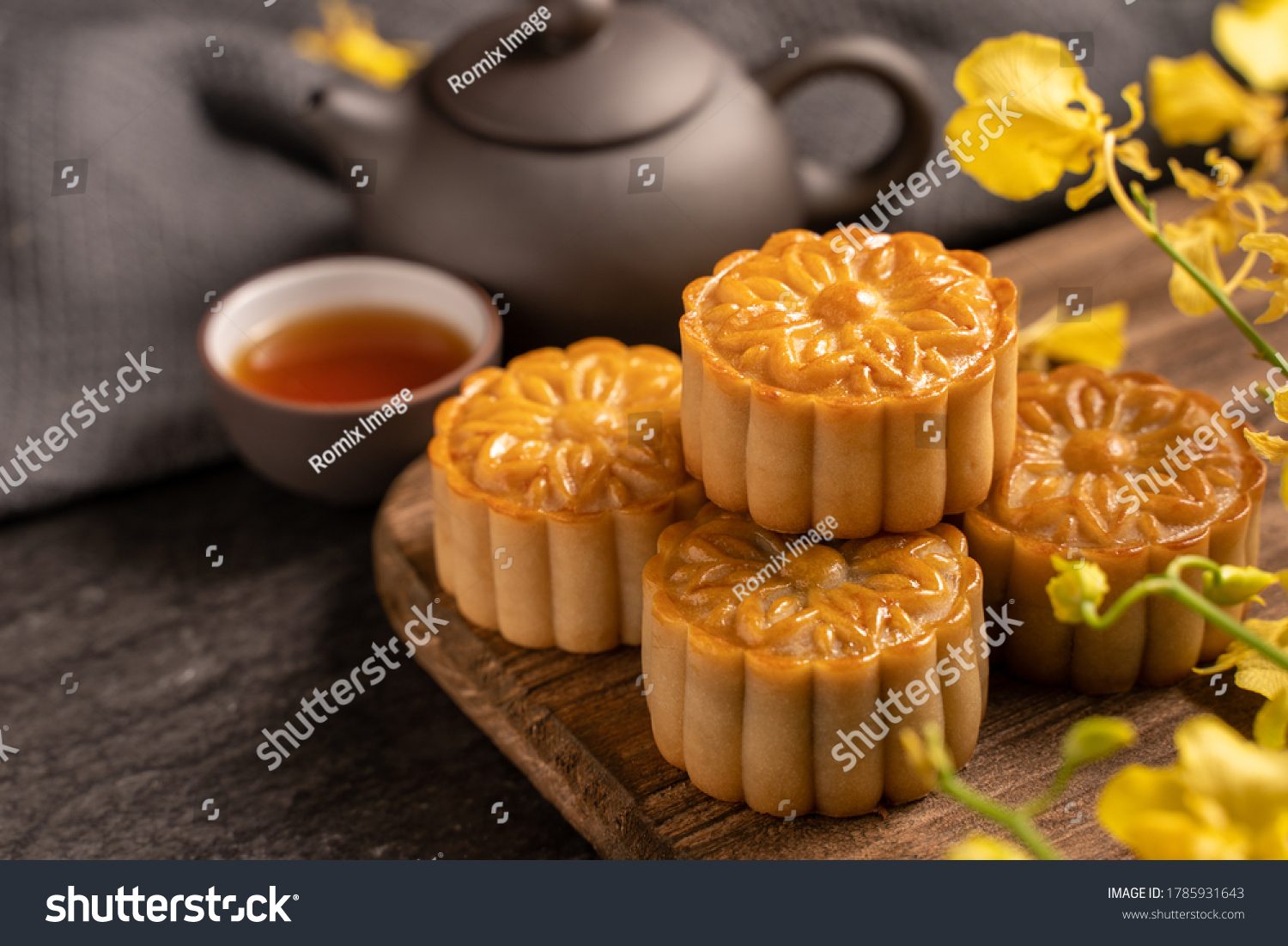 Mooncake, Moon cake for Mid-Autumn Festival, concept of traditional festive food on black slate table with tea and yellow flower, close up, copy space. #1785931643