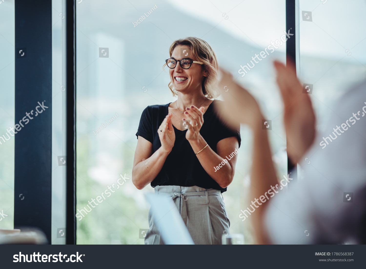 Businesswoman clapping hands after successful brainstorming session in boardroom. Business people women applauding after productive meeting. #1786568387