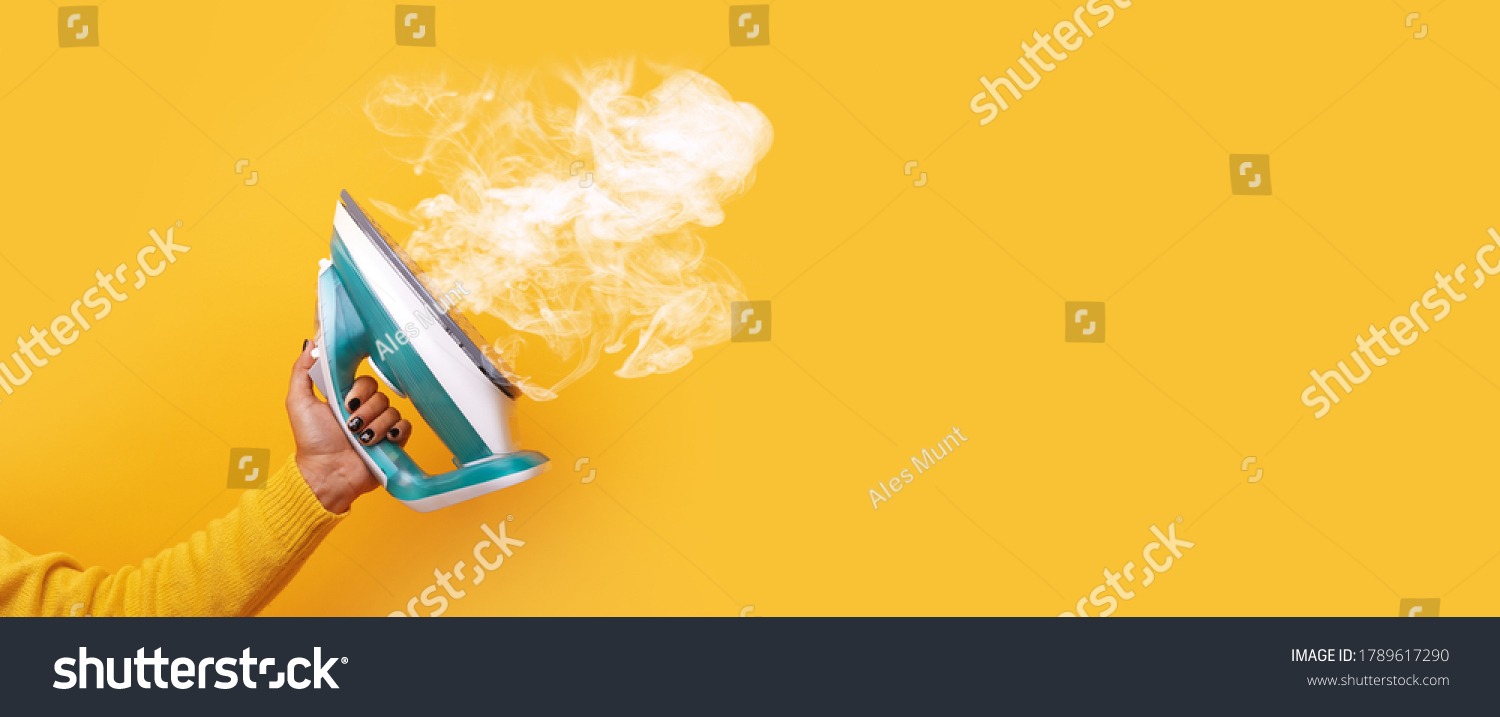 modern iron with steam in hand over yellow background, panoramic mock-up image #1789617290