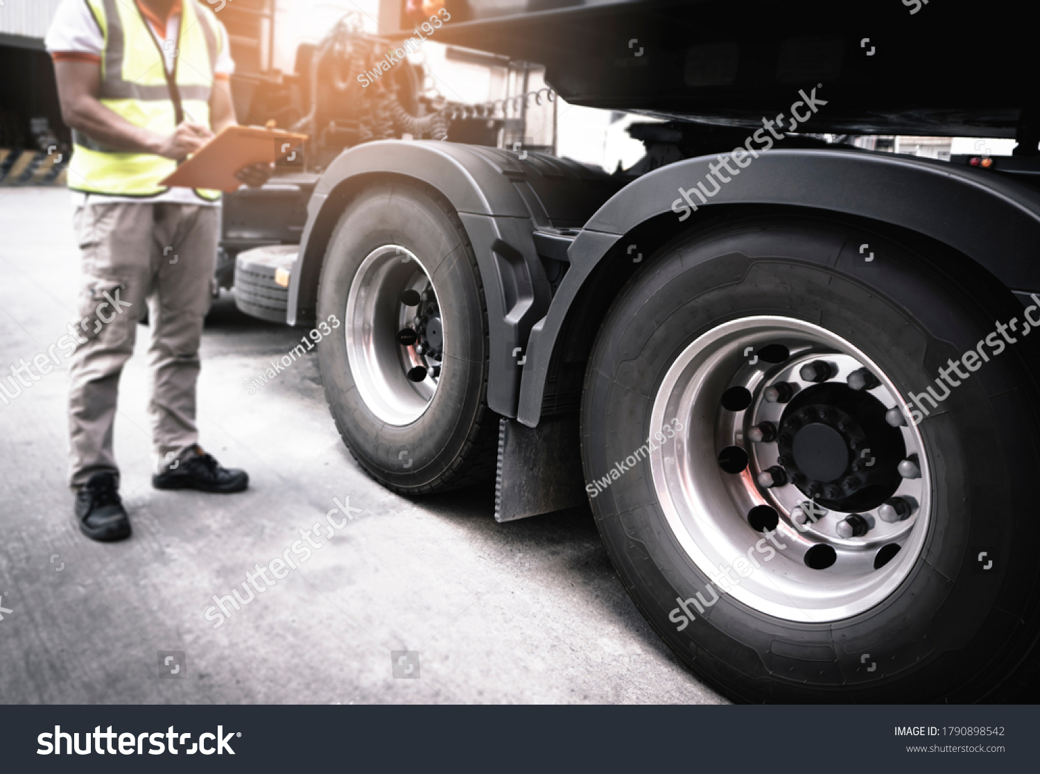 Semi truck, Maintenance and Vehicle inspection.  A truck mechanic driver holding clipboard, his safety checking a truck wheels and tires.