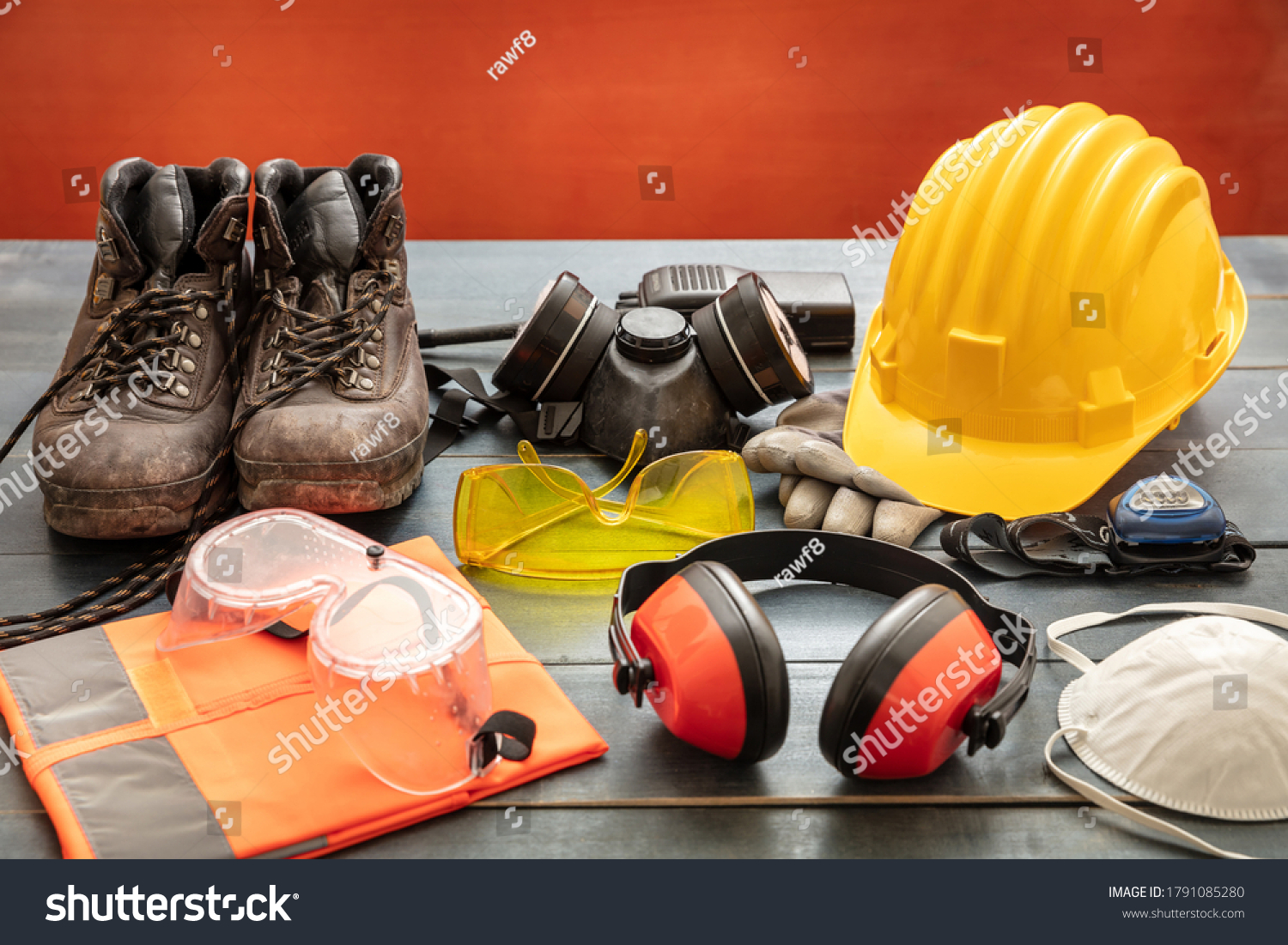 Work safety protection equipment. Industrial protective gear on wooden table, red color background. Construction site health and safety concept #1791085280