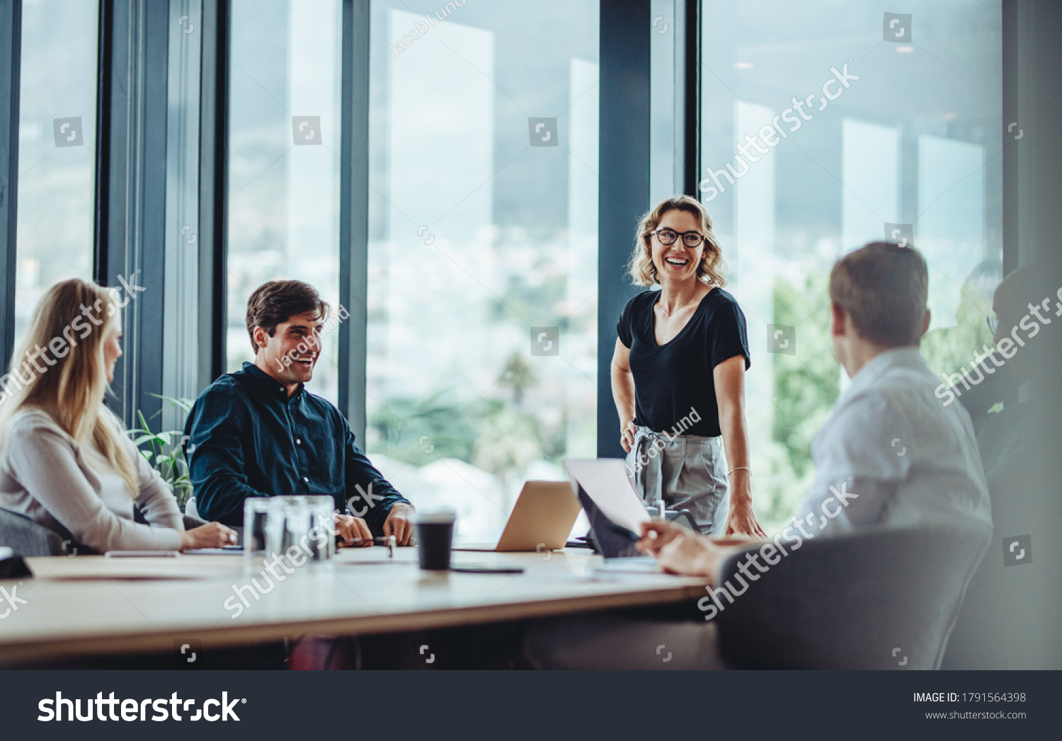 Office colleagues having casual discussion during meeting in conference room. Group of men and women sitting in conference room and smiling. #1791564398