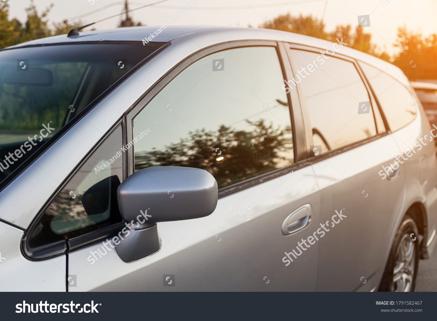 Front view of a Japanese car Honda in the body of a hatchback of the side of a silver station wagon in a parking lot with green trees after being washed ready for sale. #1791582467