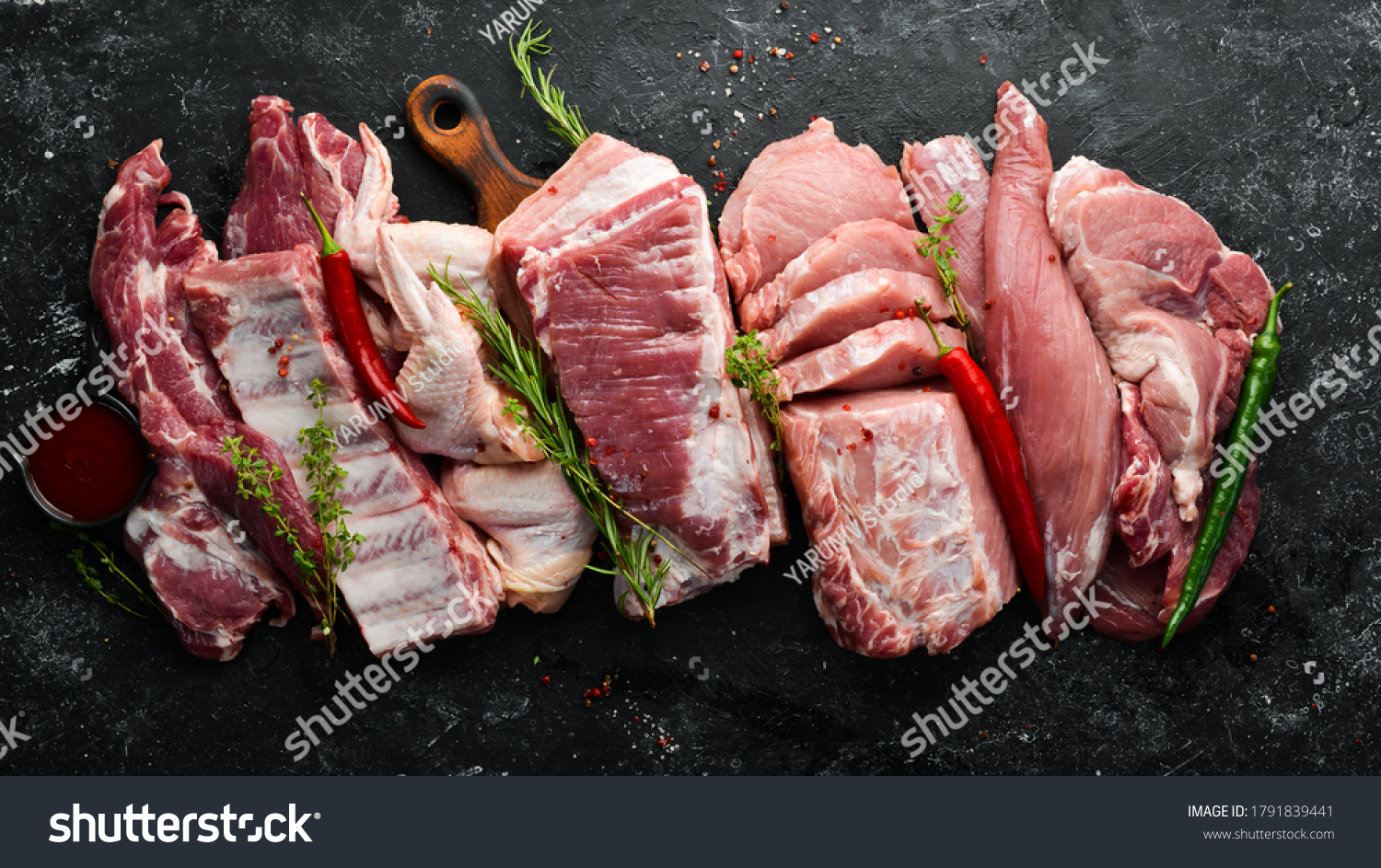 Set of raw meat. Pork meat on black stone background with spices and herbs. Top view. Rustic style. #1791839441