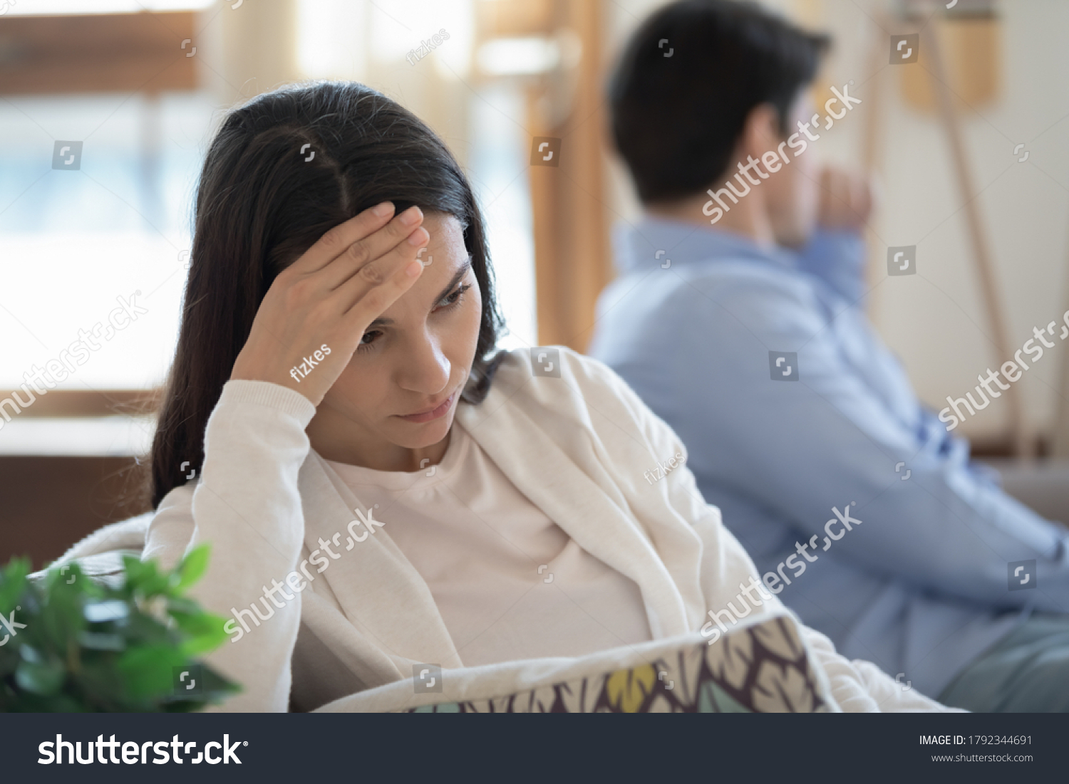 Head shot stressed confused young mixed race woman sitting in sofa separately with offended husband, ignoring each other after conflict quarrel, marriage relationship misunderstanding problem. #1792344691