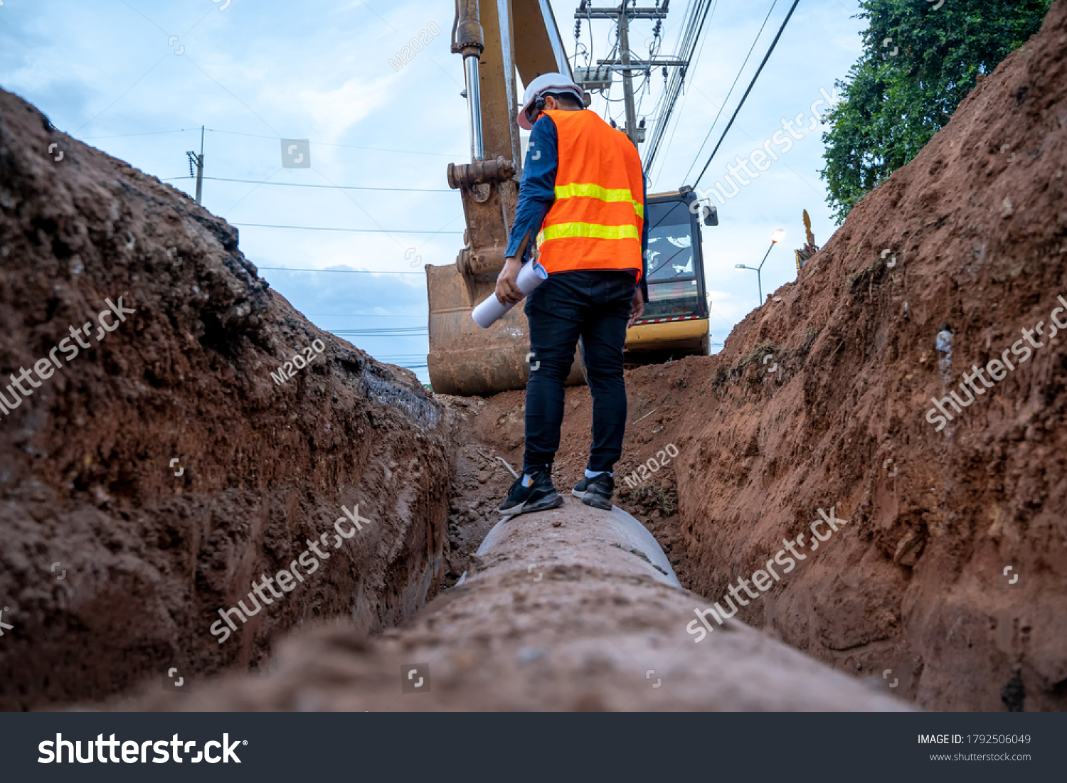 Engineer wear safety uniform examining excavation concrete Drainage Pipe and manhole water system underground at construction site. #1792506049