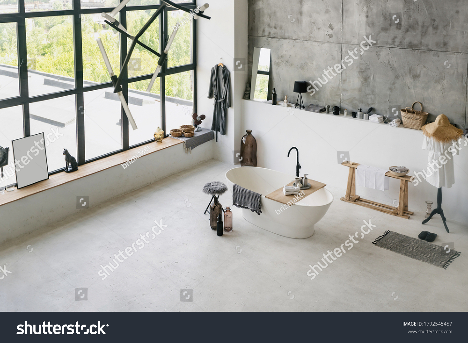 High angle view of modern interior at contemporary bathroom, folded clean towels on wooden shelf at empty bath near cotton bathrobe and house decor with copy space on concrete floor #1792545457