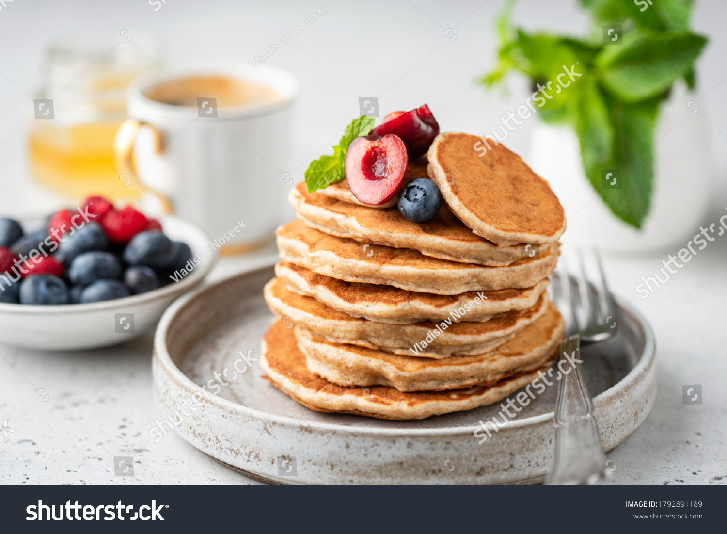 Healthy oat pancakes with berries on a craft ceramic plate. Vegan breakfast food #1792891189
