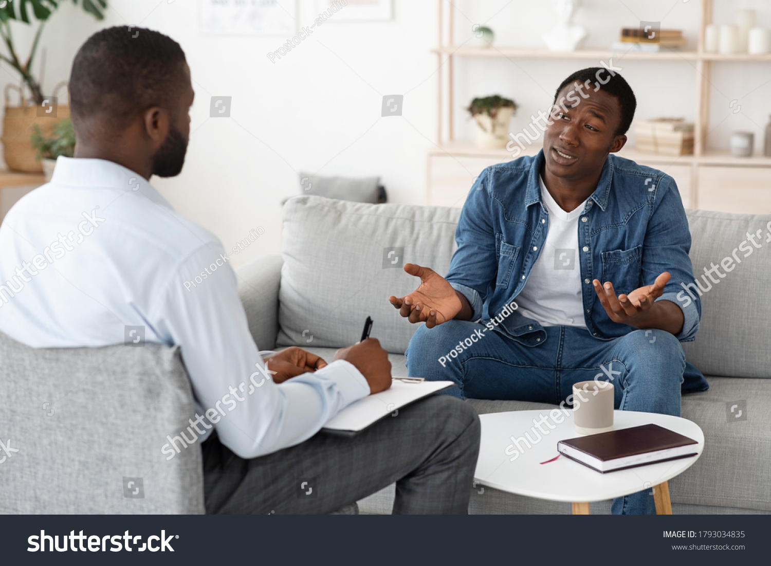 Stressed black man explaining his problems to psychologist at individual therapy session at office, copy space #1793034835