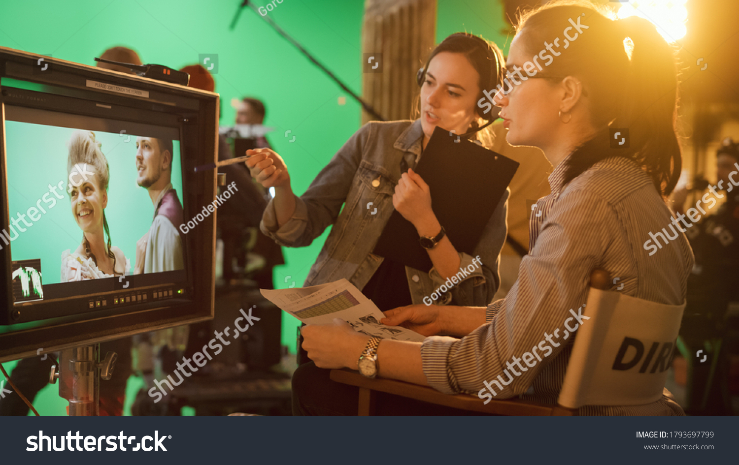Famous Talented Female Director in Chair Looks at Display talks with Assistant, Shooting Blockbuster. Green Screen Scene in Historical Drama. Film Studio Set Professional Crew Doing High Budget Movie #1793697799