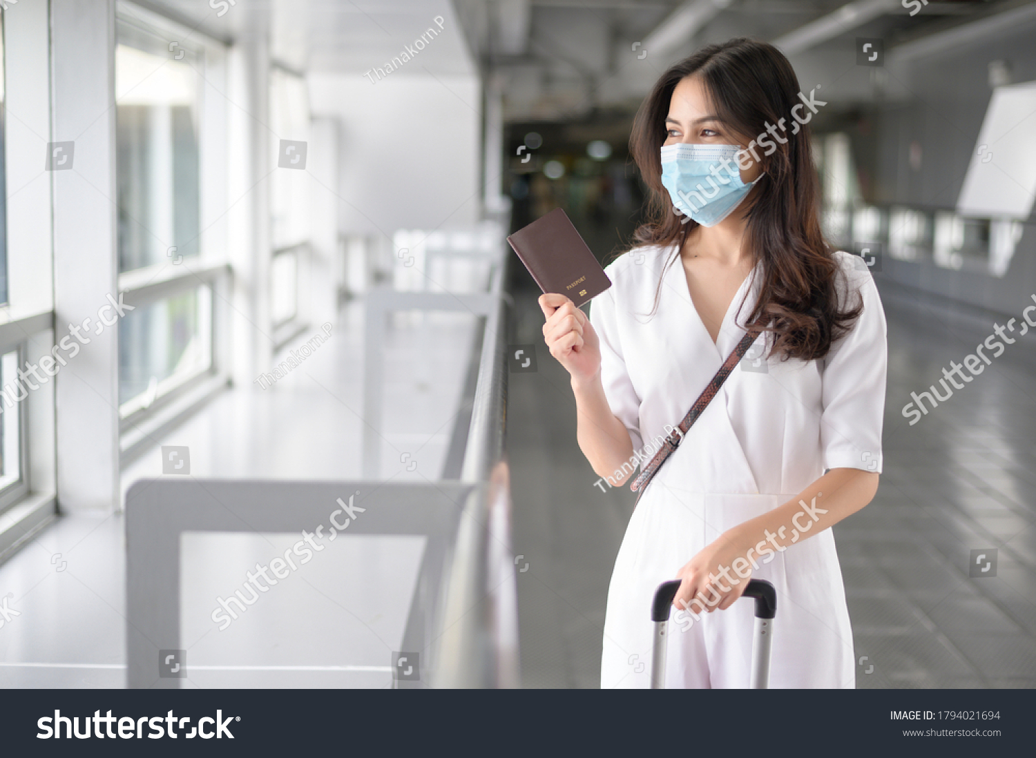 A traveller woman is wearing protective mask in International airport, travel under Covid-19 pandemic, safety travels, social distancing protocol, New normal travel concept . #1794021694