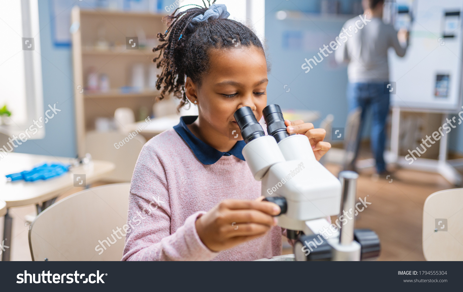 Portrait of Smart Little Schoolgirl Looking Under the Microscope. In Elementary School Classroom Cute Girl Uses Microscope. STEM (science, technology, engineering and mathematics) Education Program #1794555304
